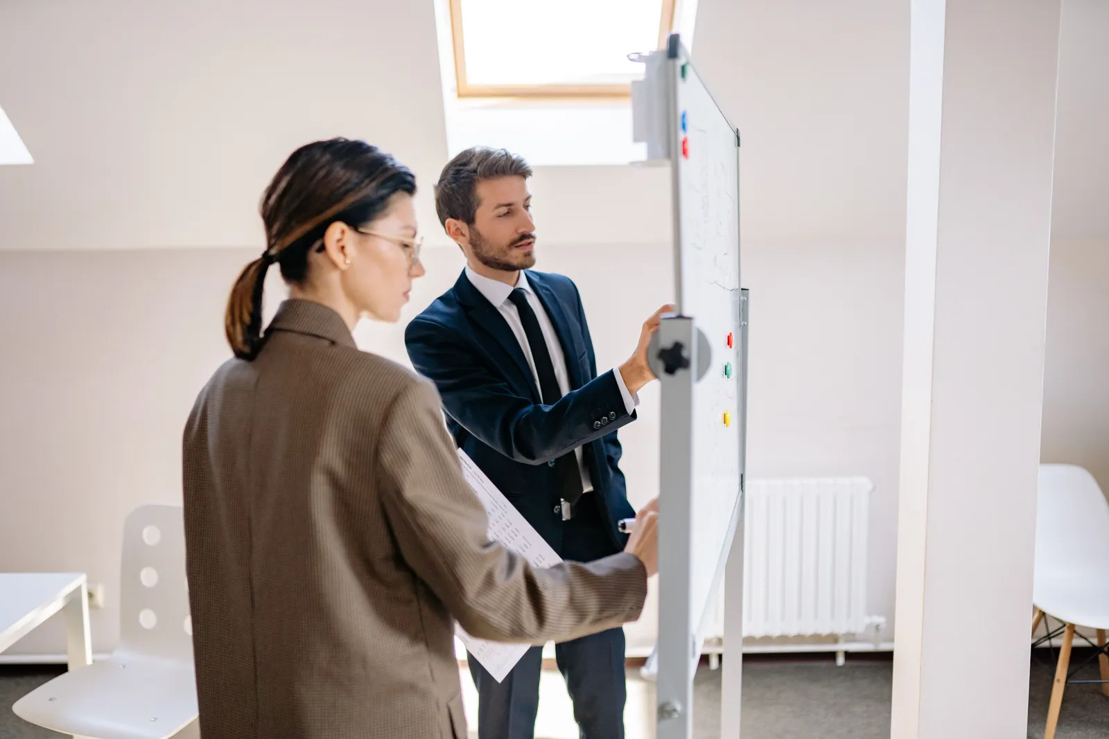 Two business professionals planning an SAP implementation at a whiteboard in a modern office